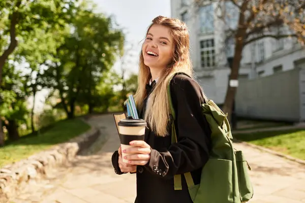 Muito jovem adulto em um uniforme elegante caminha no campus, segurando café e material escolar. — Fotografia de Stock