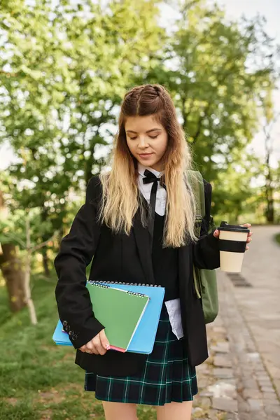 Giovane adulta in uniforme chic gode di un momento fuori con i suoi libri e caffè. — Foto stock