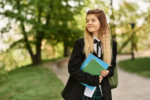 Bright and stylish young college girl smiles while walking through the campus with her notebooks. — Stock Photo