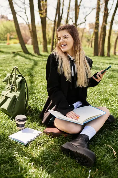 Un jeune adulte sourit assis sur l'herbe verte, étudiant et profitant du temps ensoleillé. — Photo de stock