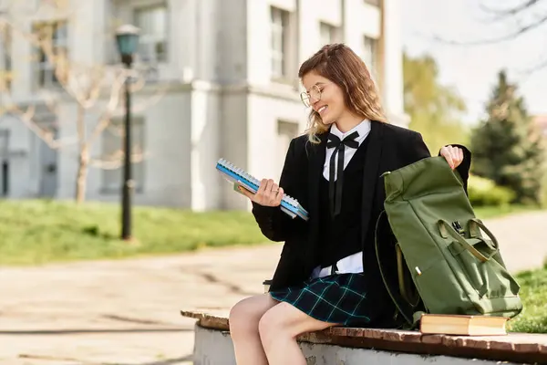 A young adult student sits on a bench outdoors, surrounded by greenery, studying her notes. — Stock Photo