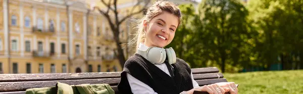 Bright and cheerful young woman in trendy outfit sits outdoors, joyfully relaxing on a bench, banner — Stock Photo