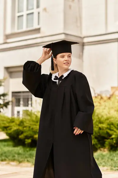 Una ragazza orgogliosa del college regola il suo berretto di laurea, abbracciando un momento di realizzazione al di fuori. — Foto stock