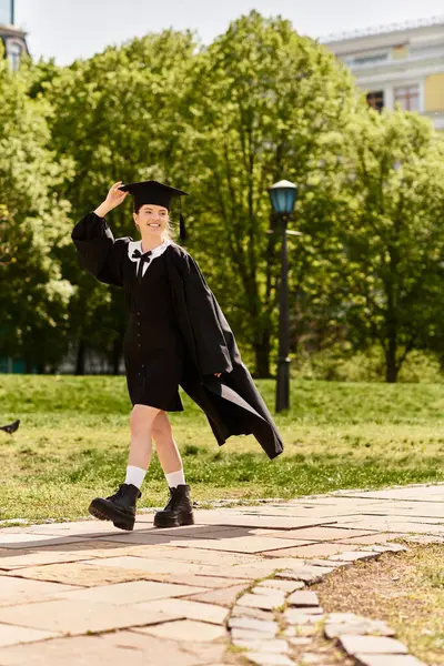 A college girl proudly walks in her graduation gown and cap, showcasing her achievement. — Stock Photo