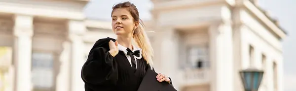 Un joven estudiante celebra la graduación, vistiendo un hermoso vestido y gorra, pancarta - foto de stock