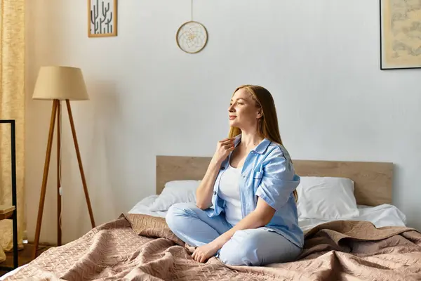 A young woman sits peacefully on her bed, savoring a moment of relaxation at home. — Stock Photo