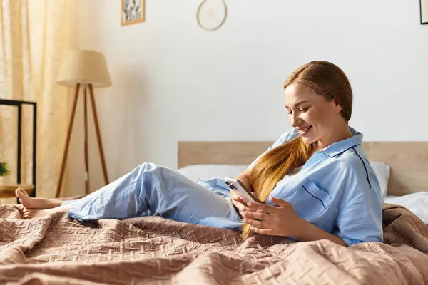 In a serene home atmosphere, a beautiful woman lounges on her bed, engaging with her phone. — Stock Photo