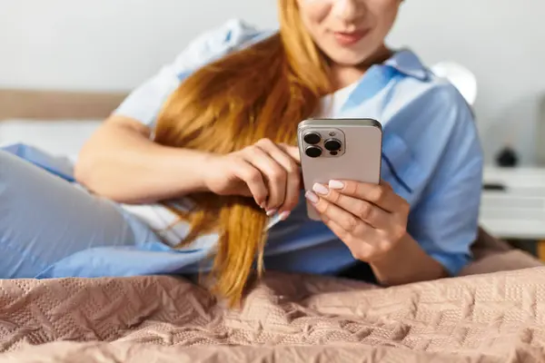 A young, beautiful woman lounges comfortably at home, engaged with her smartphone while relaxing. — Stock Photo