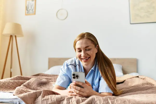 Una joven mujer disfruta de su acogedora casa, sonriendo brillantemente mientras navega en su teléfono inteligente. - foto de stock
