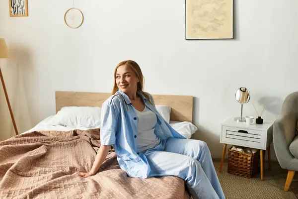 A young woman smiles warmly while seated on a cozy bed in an inviting home. — Stock Photo