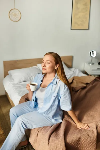 A young woman relaxes on her bed, enjoying a warm cup of coffee in a cozy room. — Stock Photo