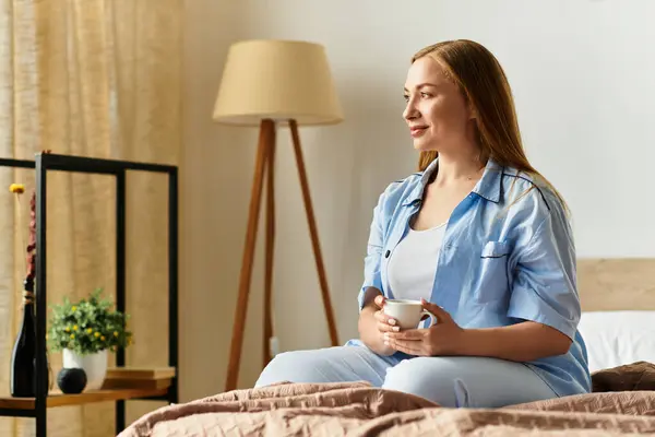 A young woman relaxes on her bed, enjoying a warm drink in a peaceful home. — Stock Photo