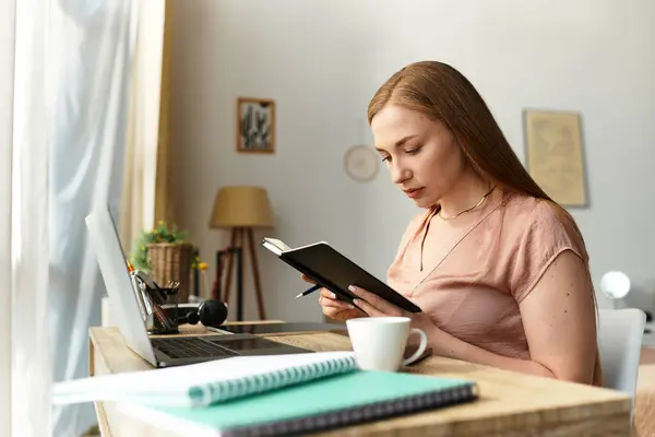 Dans un foyer chaleureux et accueillant, une jeune femme écrit dans un cahier, profondément concentrée sur ses pensées. — Photo de stock