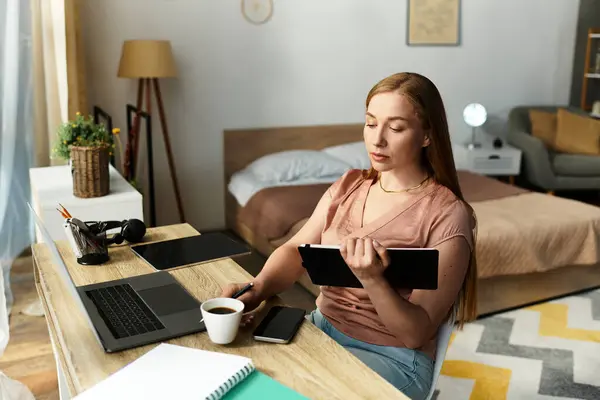 In una stanza accogliente, una giovane donna lavora creativamente alla sua scrivania con una tazza di caffè. — Foto stock