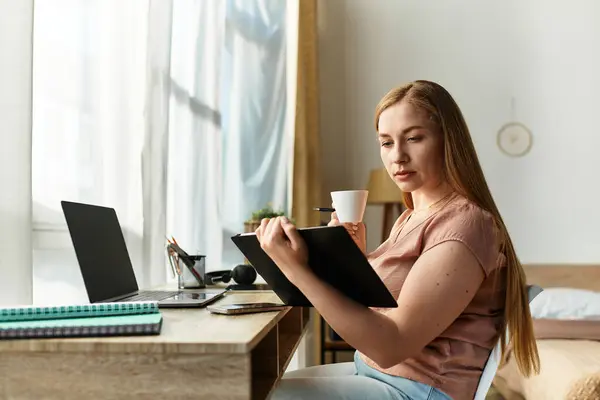 Beautiful woman focuses on her work at home, sipping coffee and enjoying the cozy atmosphere. — стоковое фото