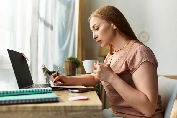 A young woman enjoys a peaceful afternoon at home, writing notes and sipping a warm drink. — Stock Photo