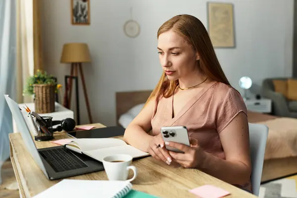 A young woman sits quietly at her desk, focused on tasks with a warm drink beside her. — Stock Photo