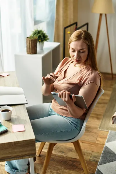 A beautiful woman relaxes in her cozy home, immersed in her tablet and enjoying a warm beverage. — Stock Photo