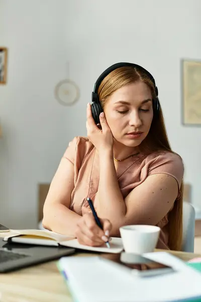 In a cozy home, a young woman relaxes, enjoying music and writing down her thoughts. — Stock Photo