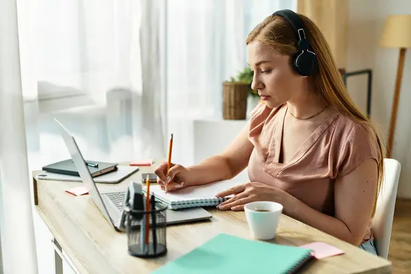 A young woman writes at a cozy desk, filled with natural light in a peaceful setting. — Stock Photo
