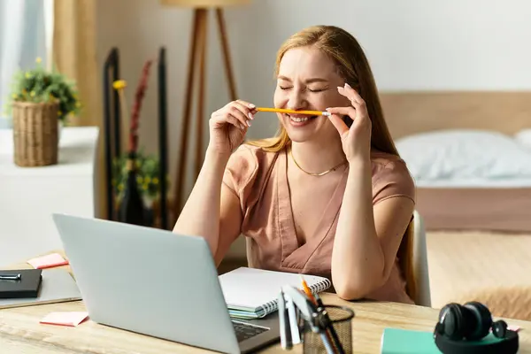 Young woman relaxes with a pencil in her mouth, smiling while working in a cozy home office. — Stock Photo