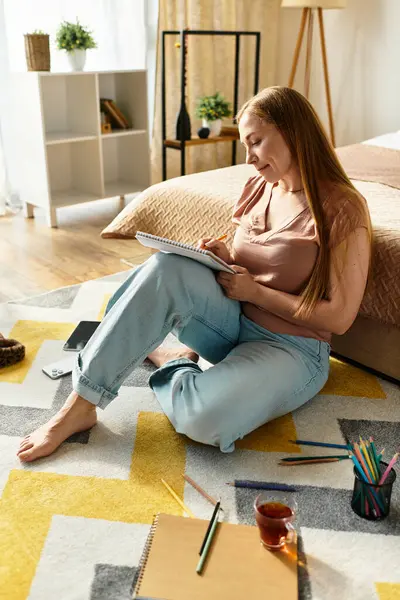 Young woman relaxes at home, writing and drawing on a sunny afternoon while sitting comfortably. — Stock Photo