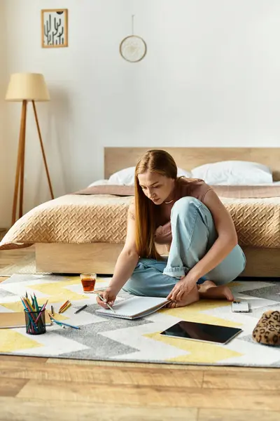 Young woman sits on the floor of her cozy bedroom, sketching various designs with vibrant pencils. — Stock Photo