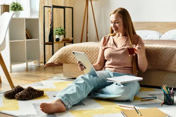 A young woman relaxes on the floor at home, savoring tea while engaged in artistic pursuits. — Stock Photo