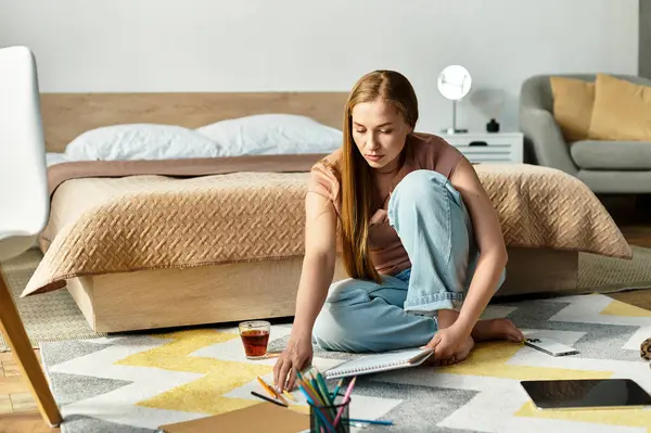 A beautiful woman sits on the floor of a cozy space, engrossed in her art. — Stock Photo