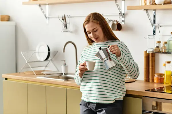 In einer gemütlichen Küche gießt eine Frau ein heißes Getränk in eine Tasse und genießt Wärme und Komfort. — Stockfoto