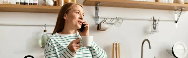 Bright kitchen with shelves filled with jars as a young woman cherishes a warm moment on a call. — Stock Photo