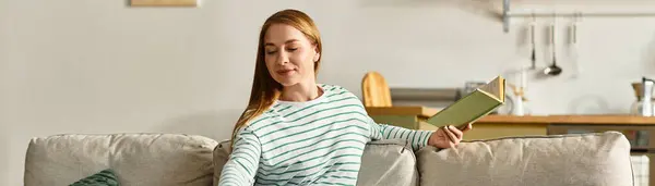 Молодая женщина расслабляется на уютном диване, наслаждаясь своей книгой в спокойном доме. — стоковое фото