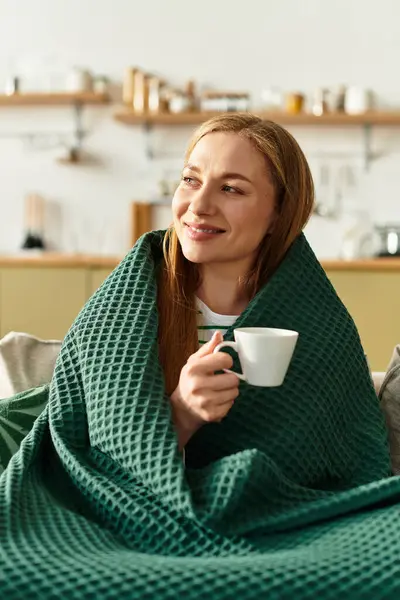 A young woman relaxes in her cozy home, sipping a warm drink and enjoying a peaceful moment. — Stock Photo