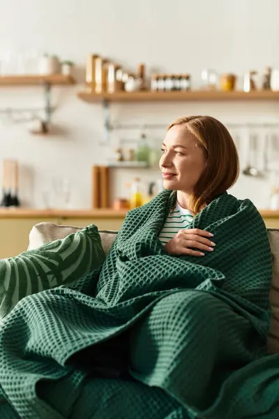 A young woman enjoys a peaceful moment wrapped in a blanket while lounging at home. — Stock Photo