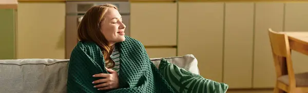 A young woman enjoys a peaceful afternoon wrapped in a soft blanket at her cozy home. — Stock Photo