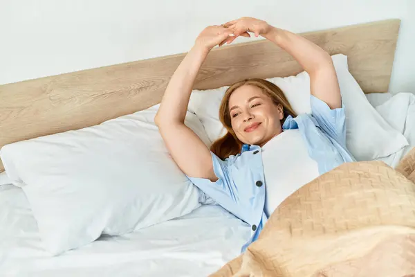 A young woman enjoys her morning routine by stretching in bed, radiating calm and happiness. — Stock Photo
