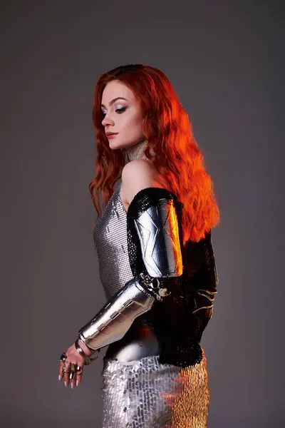 An elegant woman stands gracefully, showcasing a dazzling silver outfit and intricate armor details. — Stock Photo