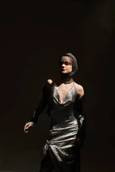 A graceful woman in shimmering attire embodies elegance in moody, castle themed lighting. — Stock Photo