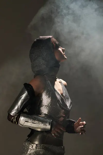 Une jeune, belle femme se tient gracieusement dans une élégante tenue métallique, mettant en valeur son style unique. — Photo de stock