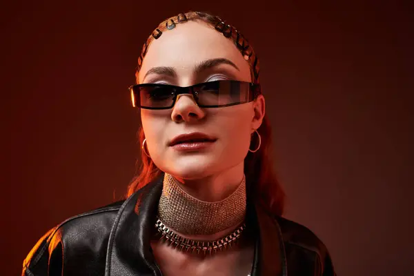 A stylish woman presents modern elegance with unique accessories against a warm backdrop. — Stock Photo