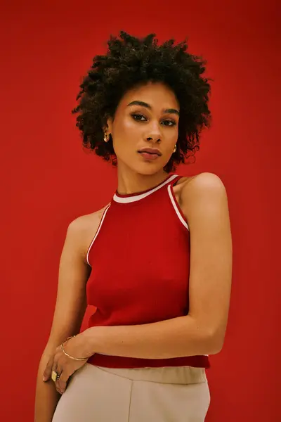 Una joven confiada posa elegantemente sobre un llamativo fondo rojo, capturando la moda moderna. - foto de stock