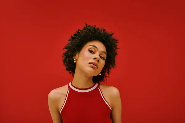 Una joven posa confiadamente sobre un atrevido telón de fondo rojo, mostrando su estilo único. - foto de stock