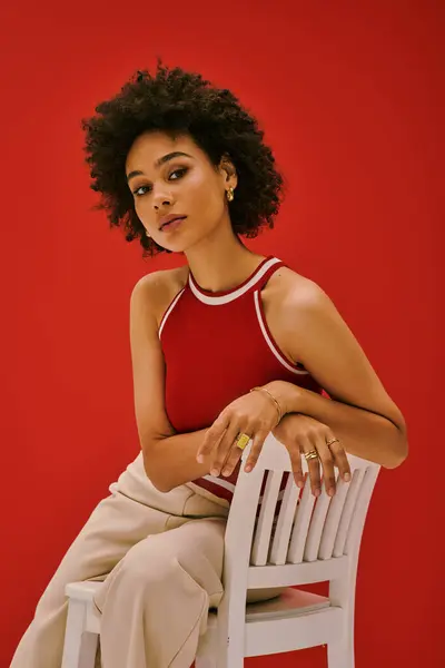 A confident young woman showcases her fashion sense while seated on a chair, radiating beauty. — Stock Photo