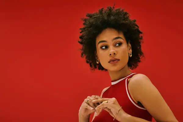 Una giovane donna posa con stile, mostrando la sua moda unica su uno sfondo rosso audace. — Foto stock