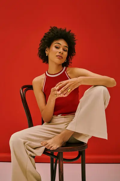 Une jeune femme confiante s'assoit élégamment sur une chaise, affichant son style unique dans un cadre vibrant. — Photo de stock