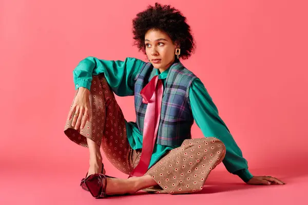 She sits elegantly with a playful pose, wearing eclectic clothing that blends colors and patterns. — Stock Photo