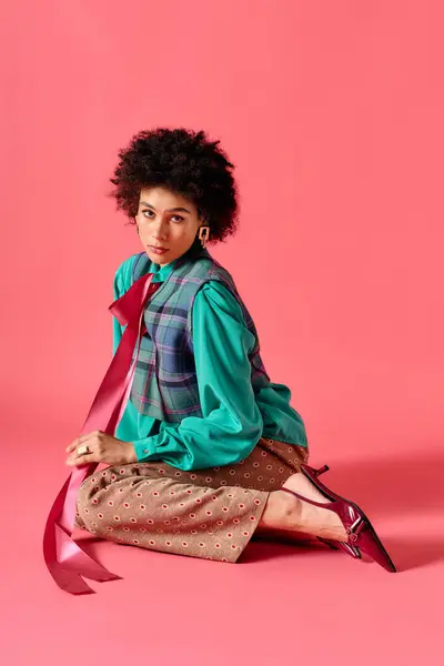 Young beautiful woman poses elegantly on a pink background wearing trendy attire with flair. — Stock Photo