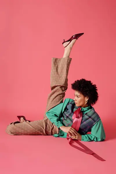 A striking young woman poses with flair, exhibiting a bold fashion choice, against a pink backdrop. — Stock Photo