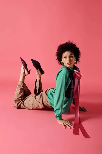 A young woman elegantly showcases modern fashion while playfully lying on her stomach. — Stock Photo
