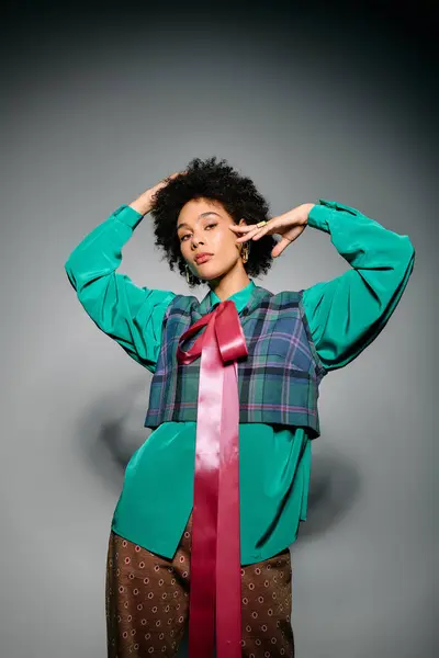 Stylish young woman poses confidently in a vibrant outfit featuring a plaid overlay and wide bow. — Stock Photo